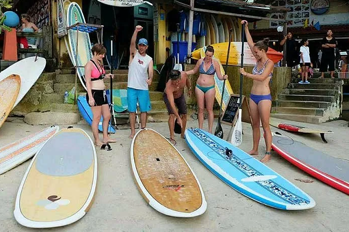 Group standing with paddleboards ready for a session on the beach